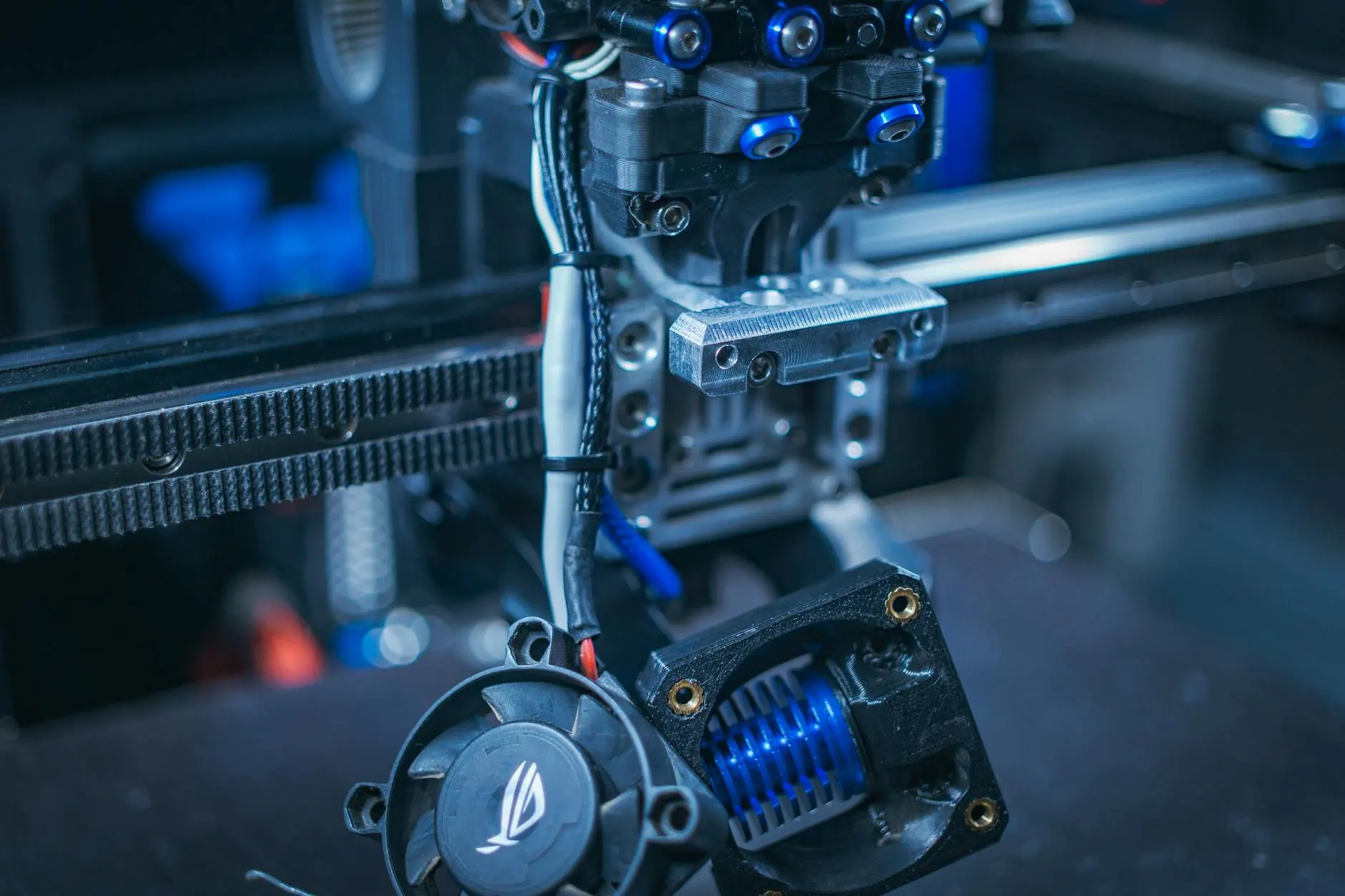 Detailed view of a 3D printer showcasing components like wires, gears, and cooling fan.